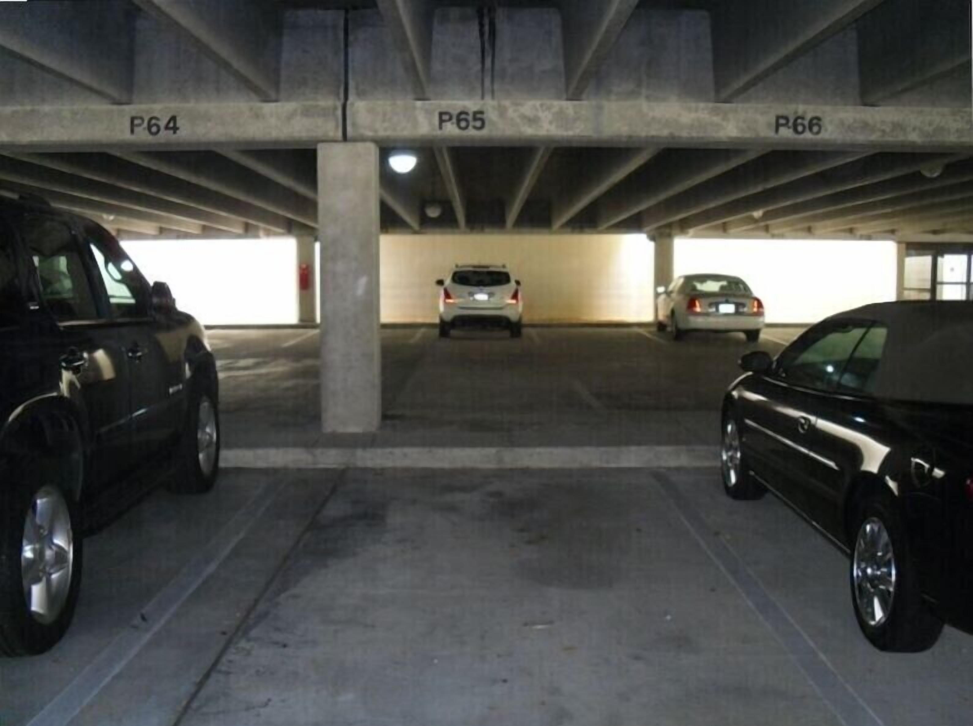 Un parcheggio con pilastri in cemento con le scritte P64, P65 e P66.
