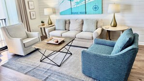 Un salon moderne comprenant un canapé, des fauteuils, une table basse et deux lampes.