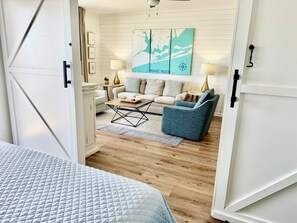 Een hotelkamer met een bed, een bank, een blauwe fauteuil, een bijzettafeltje en een muur met een kaart en kompas.