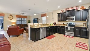 A modern kitchen with dark cabinets, stainless steel appliances, and a central island. - ⭐⭐⭐⭐⭐ChampionsGate, 9 Bed Luxury Exec Villa, Sleeps 30, West Facing Pool & Spa (Davenport)