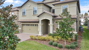 A two-story house with a garage, a stone facade, and a landscaped front yard with shrubs and a tree. - ⭐⭐⭐⭐⭐ChampionsGate, 9 Bed Luxury Exec Villa, Sleeps 30, West Facing Pool & Spa (Davenport)