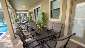 An outdoor patio with a pool, a table set for dining, and chairs. - ⭐⭐⭐⭐⭐ChampionsGate, 9 Bed Luxury Exec Villa, Sleeps 30, West Facing Pool & Spa (Davenport)