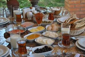 A table set with various food items and drinks, including bowls of olives, cheese, eggs, and bread, along with glasses of tea and milk. - Talıstan Forest Park (Ismailli)