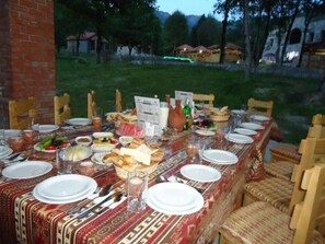 A long dining table set outdoors with various dishes, glasses, and a menu. - Talıstan Forest Park (Ismailli)