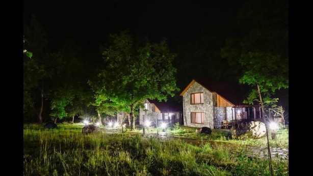 Un edificio de piedra con techo rojo, rodeado de árboles e iluminado por luces.