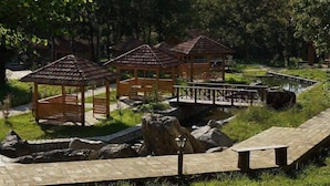 Un parque con quioscos de madera, un puente de piedra y un estanque.