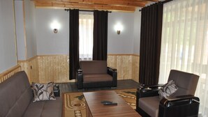 Una sala de estar con un sofá, dos sillones, una mesa de centro y un televisor.