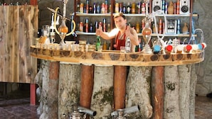 Un bar con base de madera y estantes llenos de botellas y vasos.