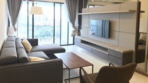 A modern living room with a sectional sofa, a flat-screen TV, and a minimalist design. - The Landmark Penthouse Luxury Condo by Casa Accommodation (George Town)