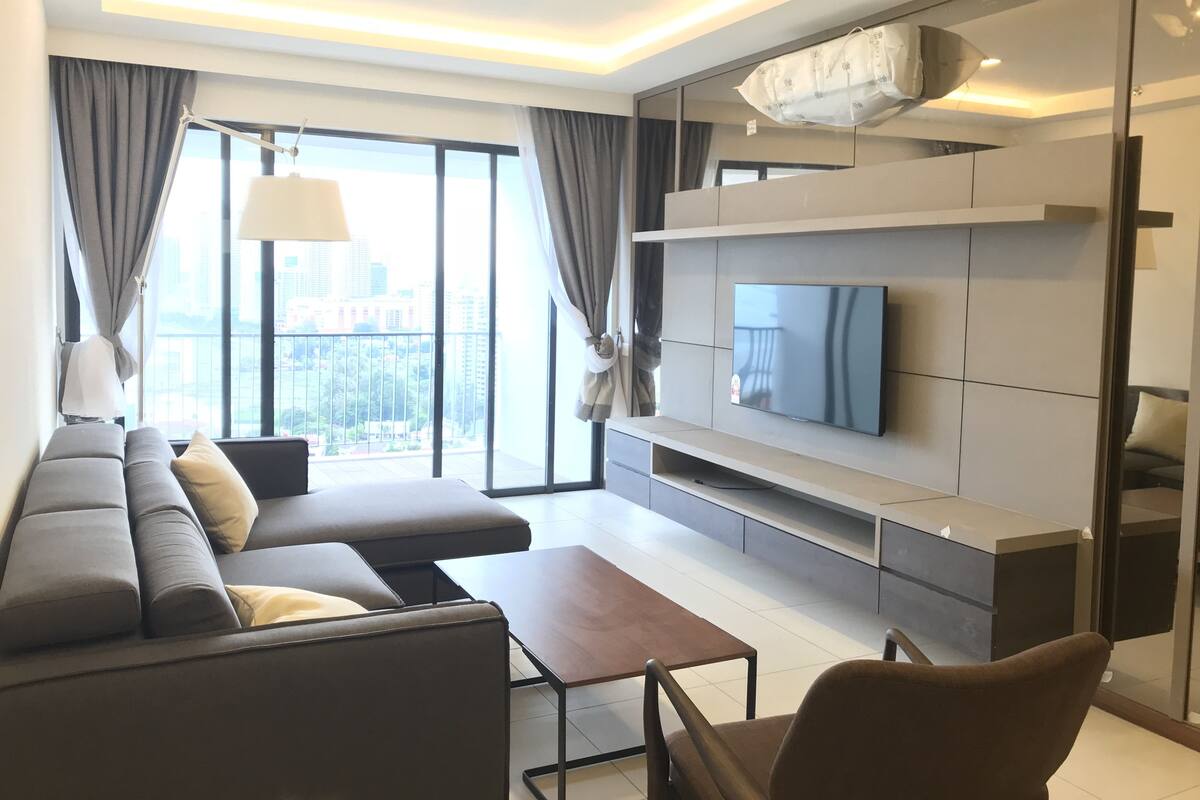 Un salon moderne avec un canapé d’angle, un téléviseur à écran plat et un design minimaliste.