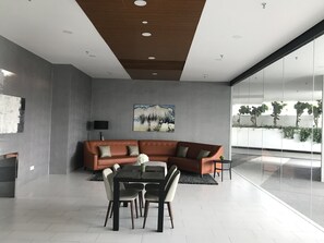 Un salon moderne avec un canapé d’angle, une table à manger avec des chaises, un téléviseur à écran plat et un tableau accroché au mur.
