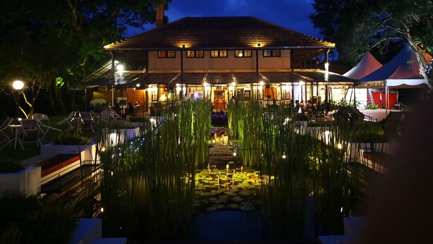 A building with a tiled roof, a pond with water lilies, and outdoor seating. - The Landmark Penthouse Luxury Condo by Casa Accommodation (George Town)