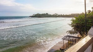 A beach with a clear view of the ocean and a distant island with buildings. - Villa Surf Beach (Galle)