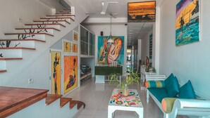 A modern interior with a staircase, artwork, a sofa, and a table with a plant. - Villa Surf Beach (Galle)