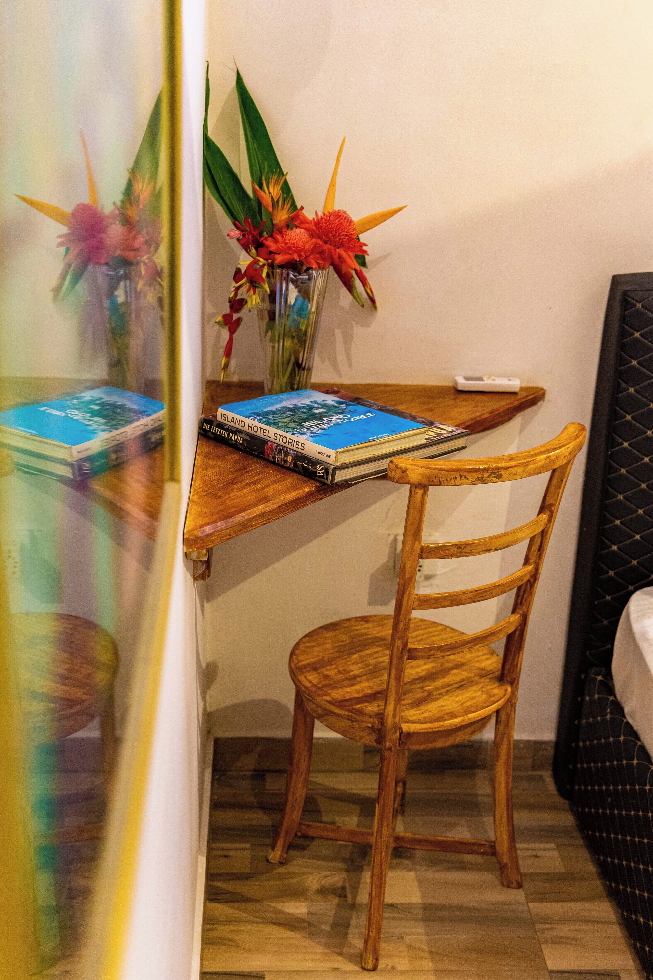 Une chaise en bois et une petite table avec des livres et un vase de fleurs, placés dans un coin de la pièce.