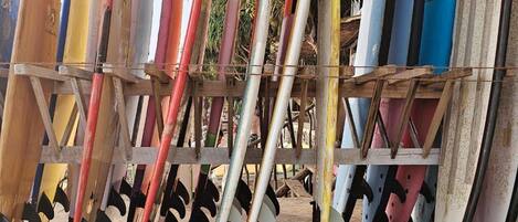 Varias tablas de surf apoyadas contra una estructura de madera al aire libre.