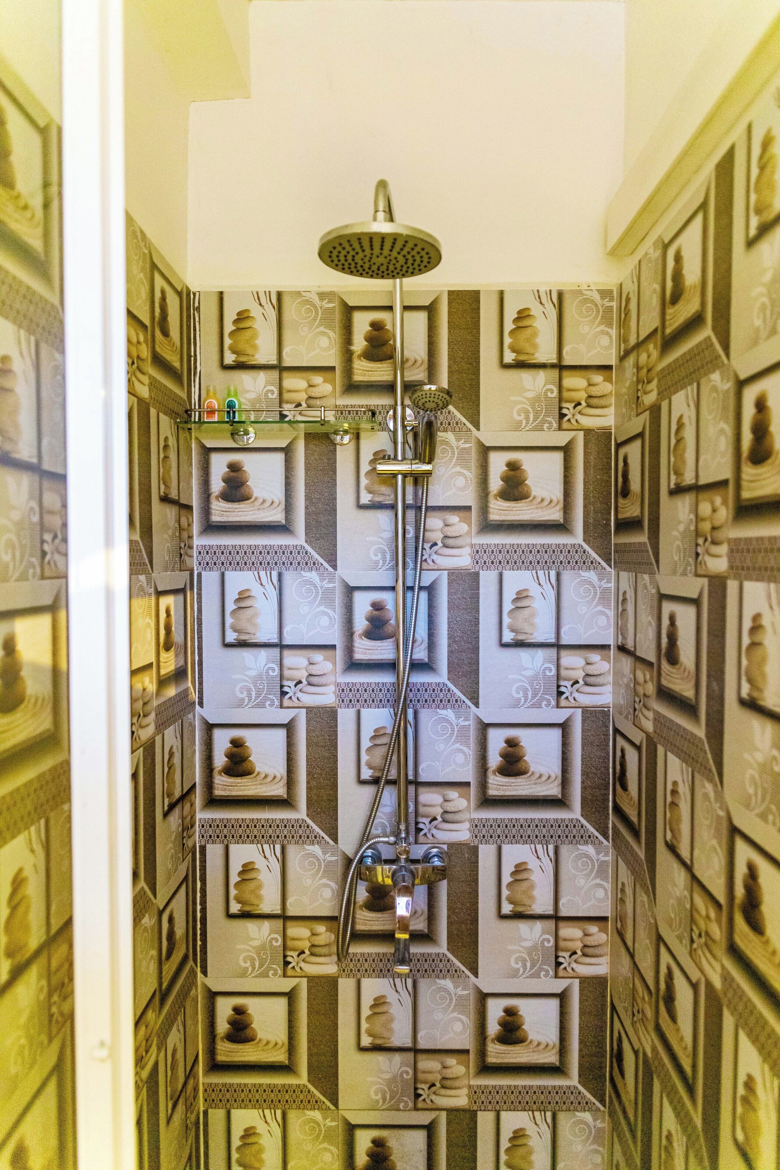 A bathroom with a shower, tiled walls, and framed pictures.