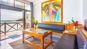 A modern living room with a wooden coffee table, a sofa, and a large painting of elephants. - Villa Surf Beach (Galle)