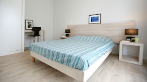 Een slaapkamer met een bed, nachtkastjes, een stoel en een lijst met een afbeelding aan de muur.