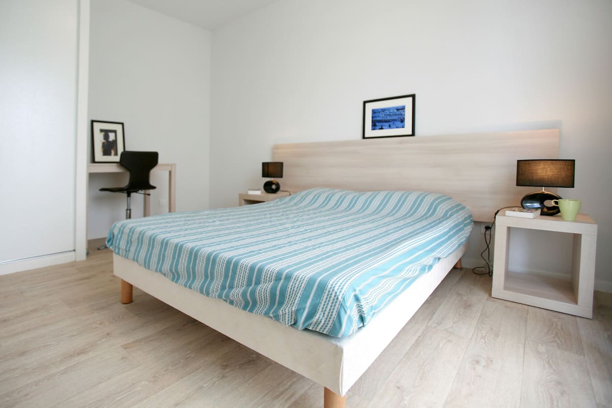 Une chambre à coucher avec un lit, des tables de chevet, une chaise et un tableau encadré au mur.
