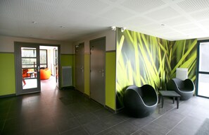 Un espace d’attente moderne agrémenté d’un mur végétal, de sièges et d’une porte donnant sur l’extérieur.
