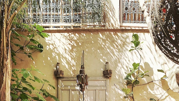 Un patio con una puerta de madera grande, un farol colgante y una reja de hierro forjado.