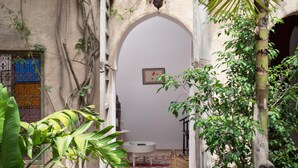 Un patio interior con suelo de baldosas, una mesa blanca y un farol colgante.
