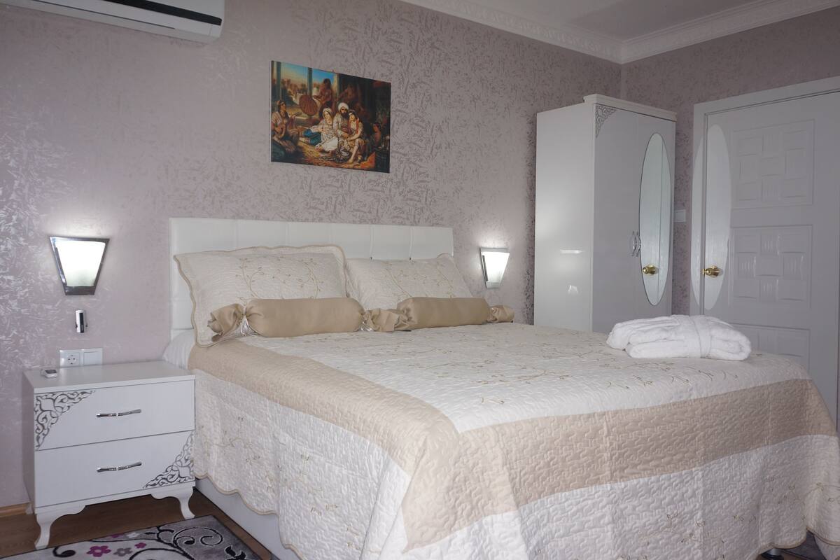 Une chambre à coucher avec un grand lit, une table de chevet, une armoire et un tableau au mur.