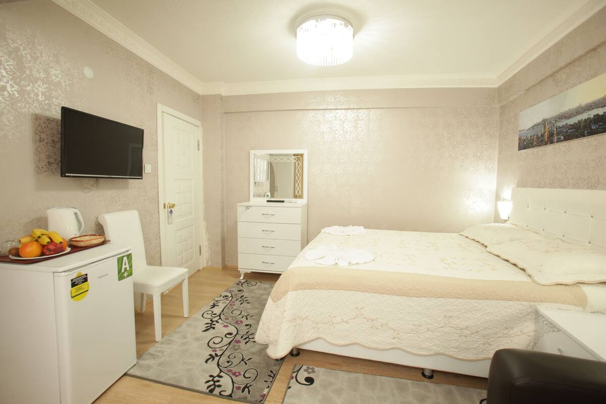 Une chambre à coucher comprenant un lit, une commode, un téléviseur et un réfrigérateur.