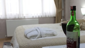 A hotel room with a bed, a bottle of wine, and a glass of wine on a table. - Hotel Terrace Istanbul (Istanbul)