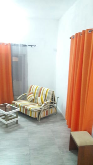 A living room with a striped sofa, a small table, and orange curtains.
