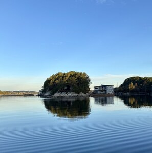 Un lago tranquilo con una pequeña isla que presenta una casa y un muelle.