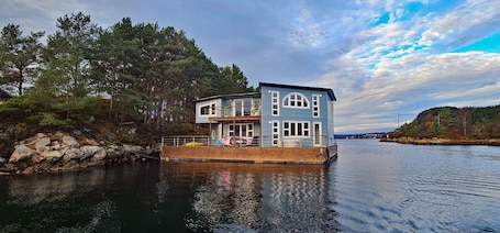 A waterfront house with a wooden deck, large windows, and a dock.. Floating Villa Bergen