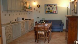 Una cocina compacta con comedor, un sofá azul y un cuadro en la pared.
