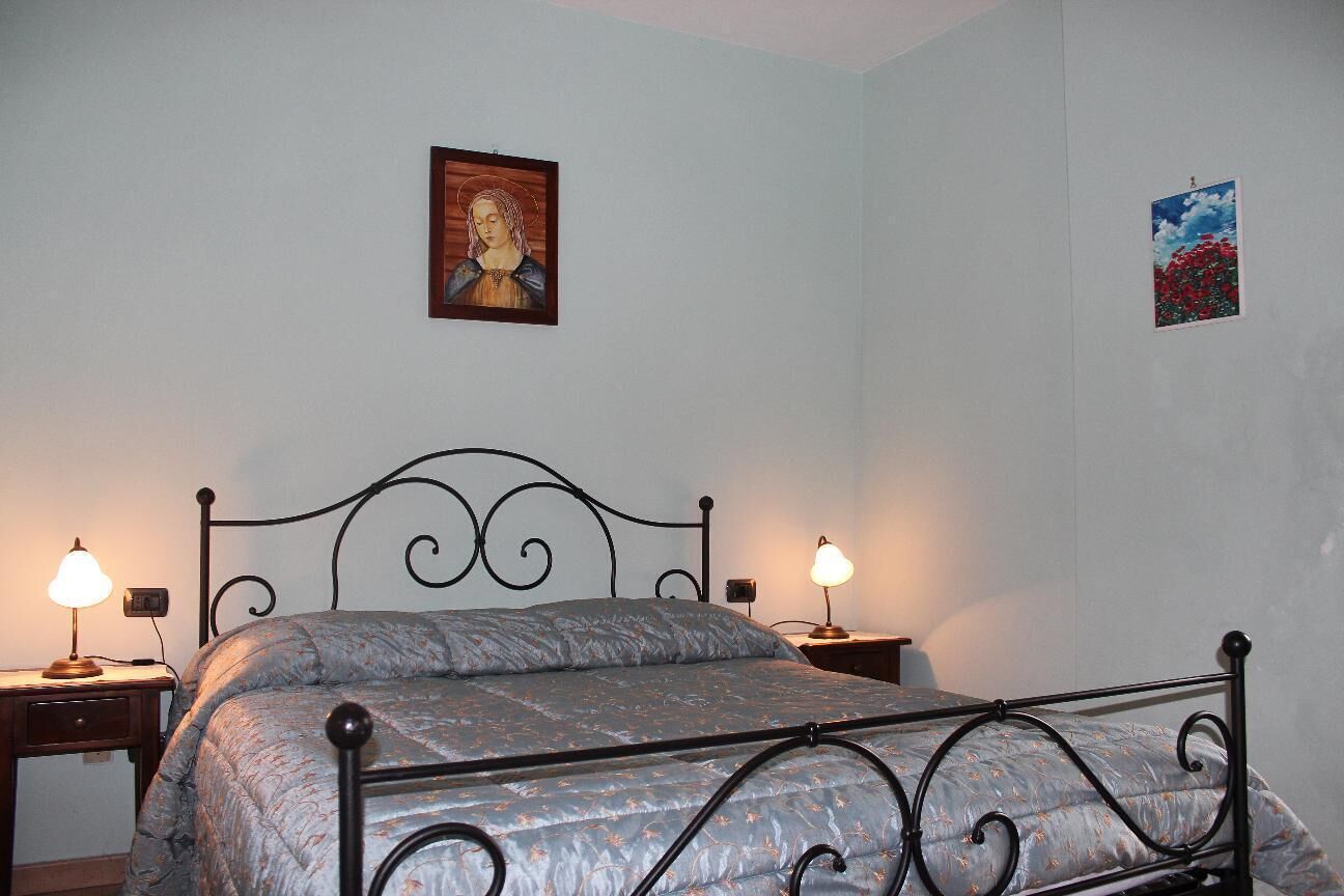 Ein Schlafzimmer mit einem Metallbettgestell, zwei Nachttischen mit Lampen, einem Wandbild und einem kleinen gerahmten Bild.