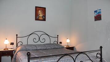 Ein Schlafzimmer mit einem Metallbettgestell, zwei Nachttischen mit Lampen, einem Wandbild und einem kleinen gerahmten Bild.