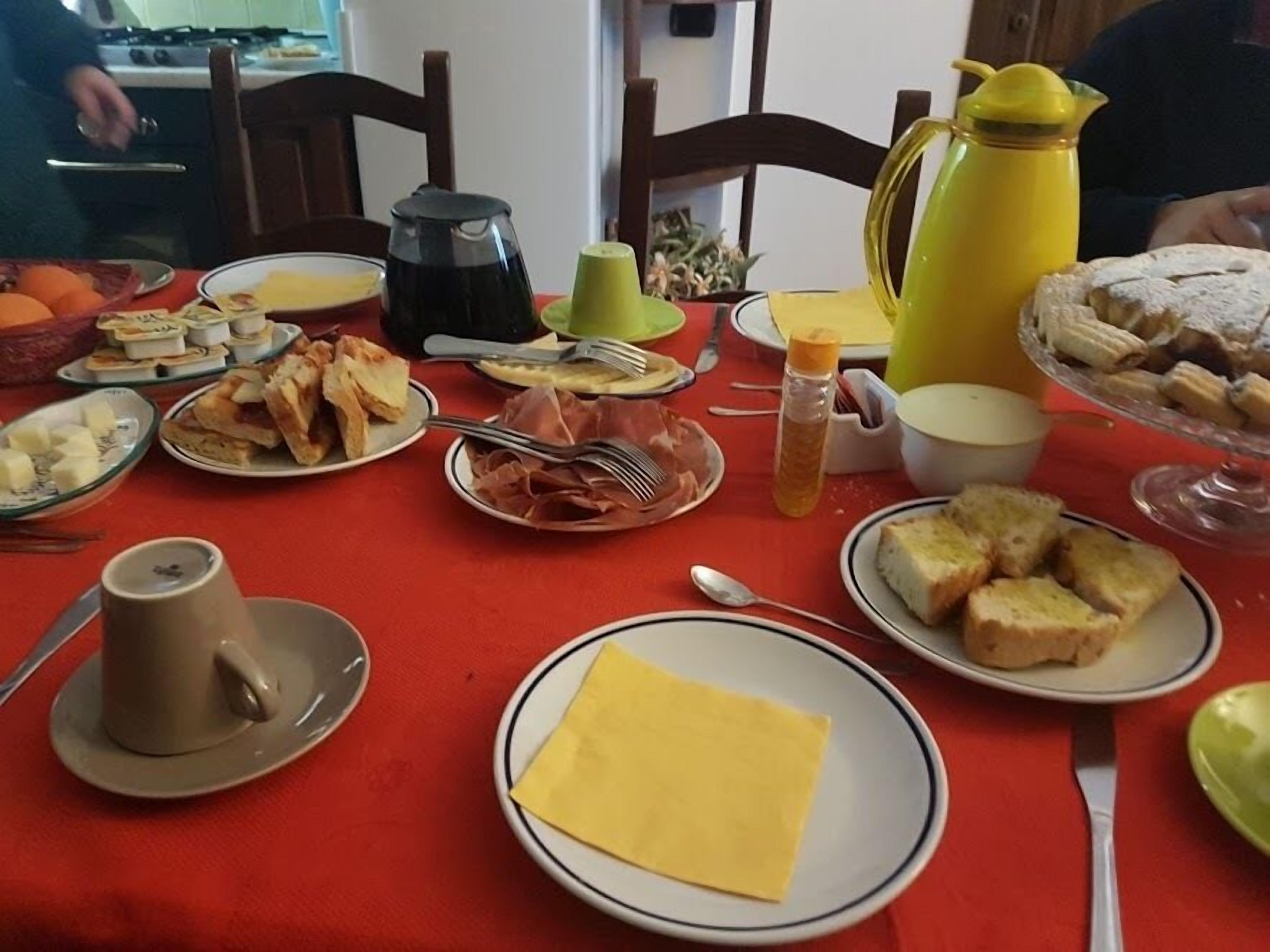 Una mesa de comedor dispuesta con diversos platos, incluyendo pan, queso y una jarra.