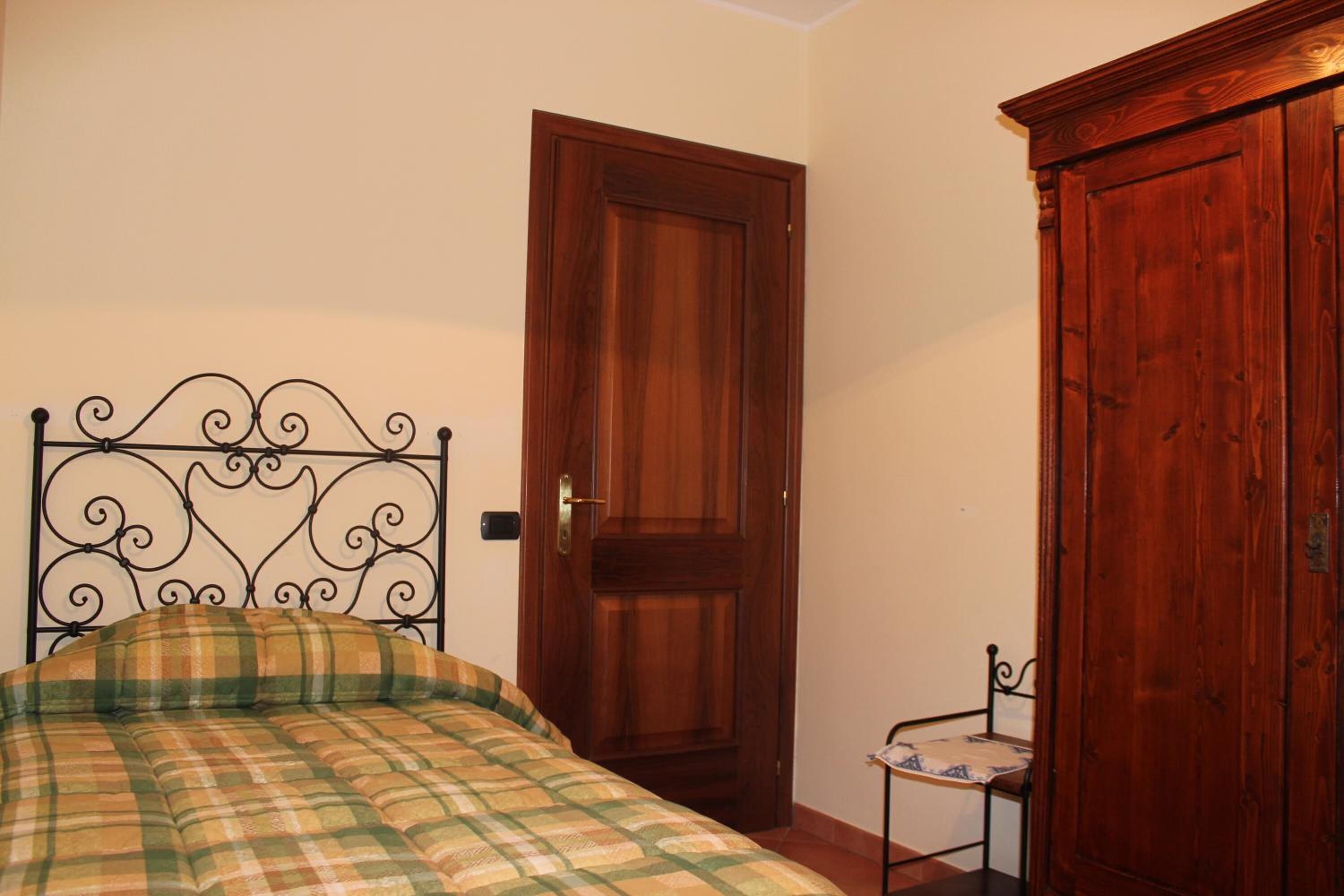 Quarto com cama, porta de madeira e uma mesinha.