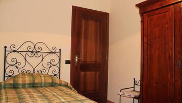 Quarto com cama, porta de madeira e uma mesinha.