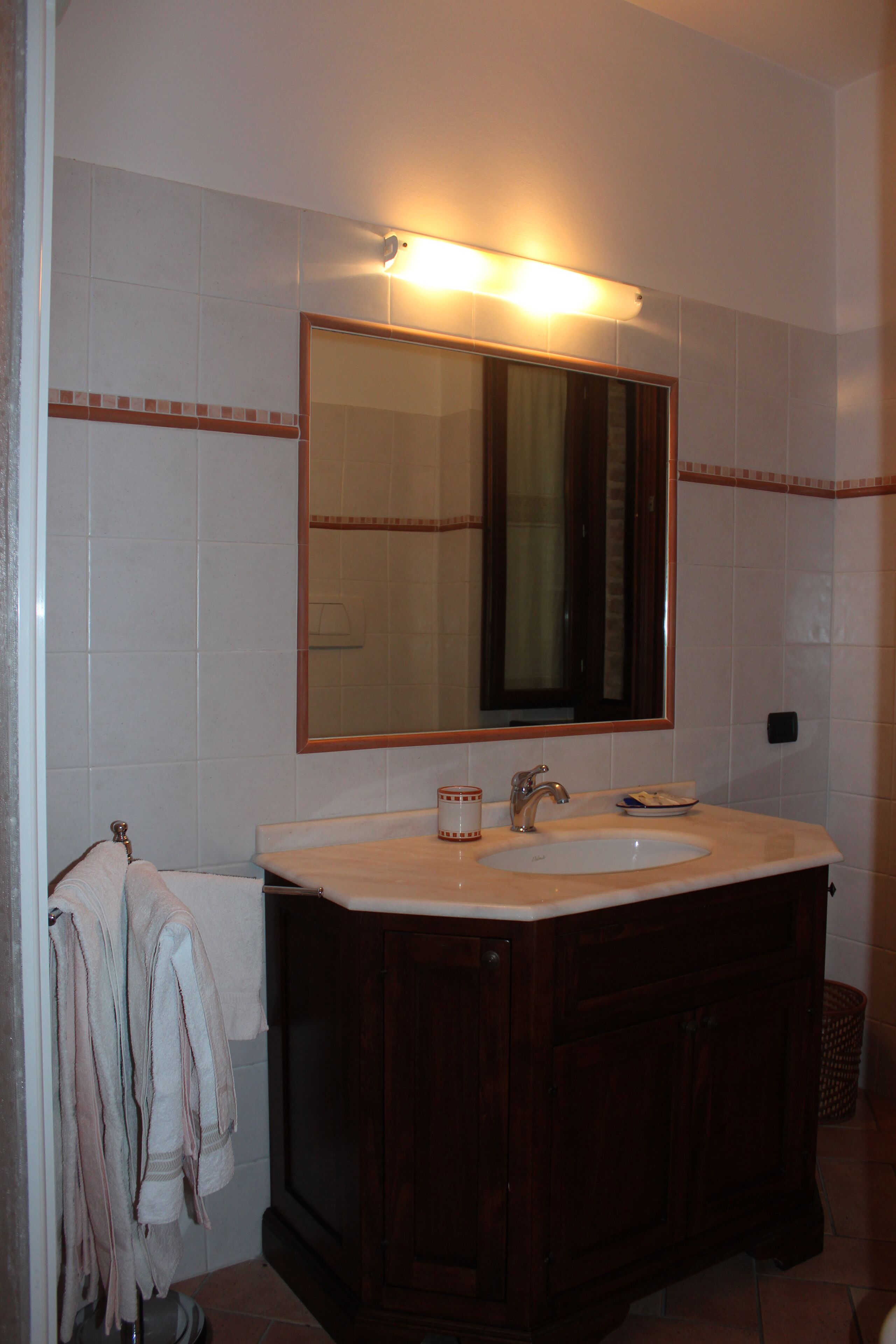 Un baño con un espejo grande, un lavabo y armarios de madera.
