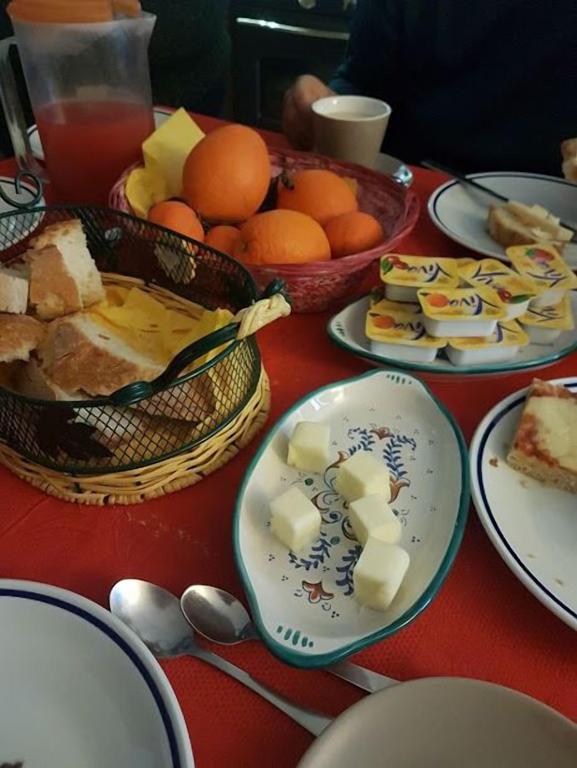 Ein Tisch mit Speisen, darunter Brot, Käse, Orangen und ein Getränk.