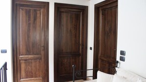 Una habitación con tres puertas de madera, una cama con estructura de metal y una pared blanca.