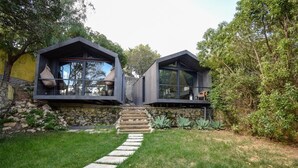 A modern house with two large, dark-colored rooms with large windows, a stone wall, and a stone staircase leading to the entrance. - Village Cascais Guest House (Cascais)