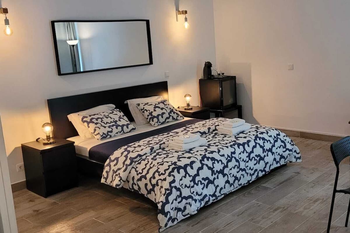 A bedroom with a bed, bedside tables, a nightstand, a chair, a table, and a sofa.
