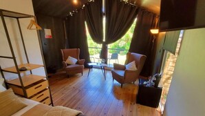A cozy room with a bed, two armchairs, a small table, and a TV. - Village Cascais Guest House (Cascais)