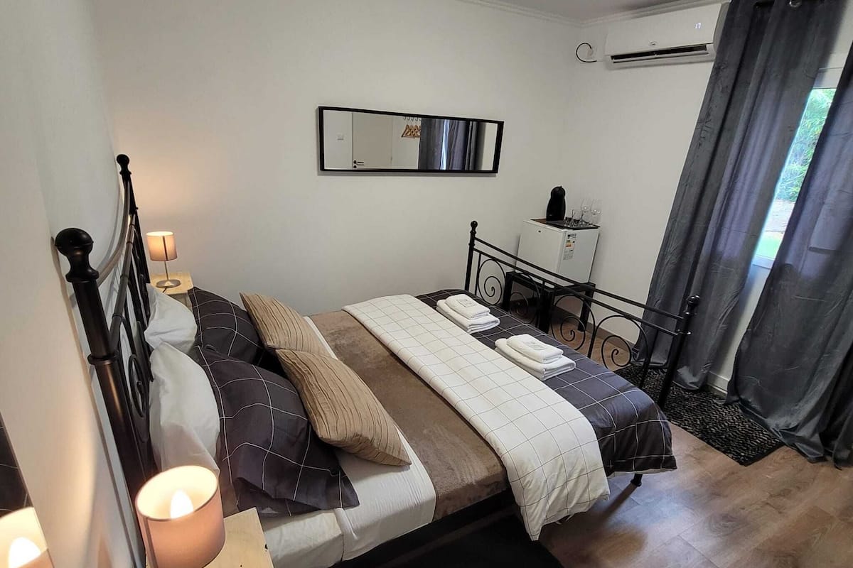 A bedroom with a bed, bedside table, lamp, and a mirror on the wall.