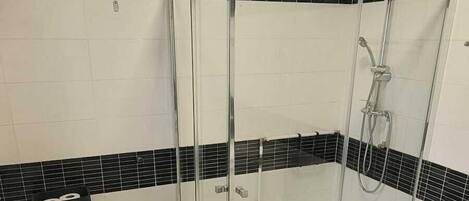 A bathroom with a glass-enclosed shower, a toilet, and a bidet.