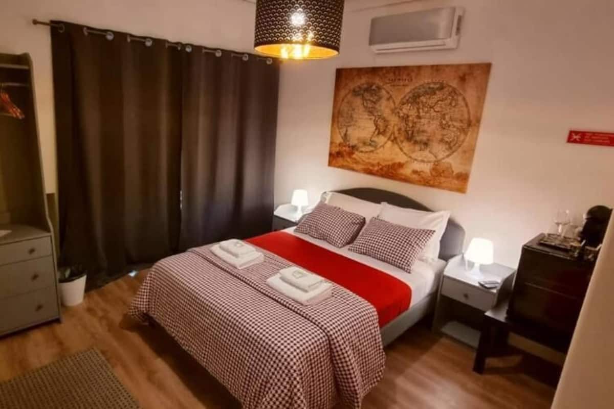 A bedroom with a bed, bedside tables, a wardrobe, a map on the wall, and a hanging light fixture.