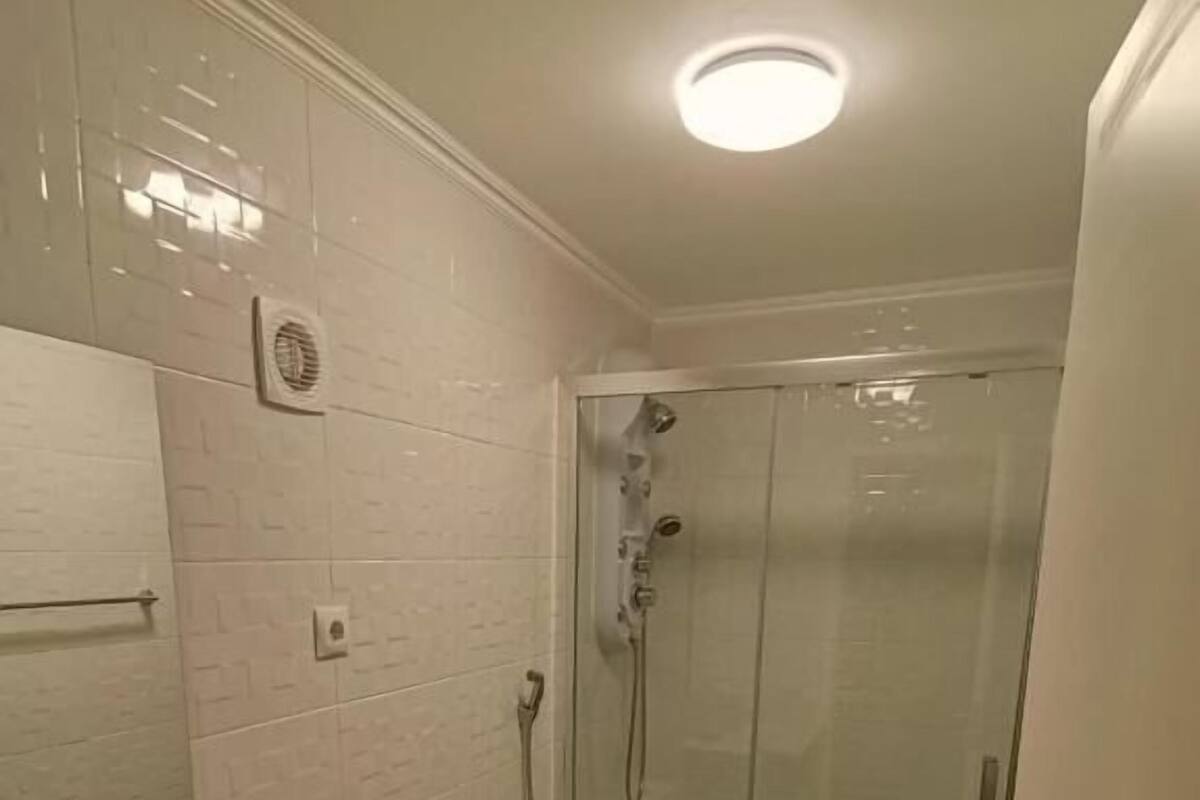 A bathroom with a glass-enclosed shower, a white sink, and a toilet.