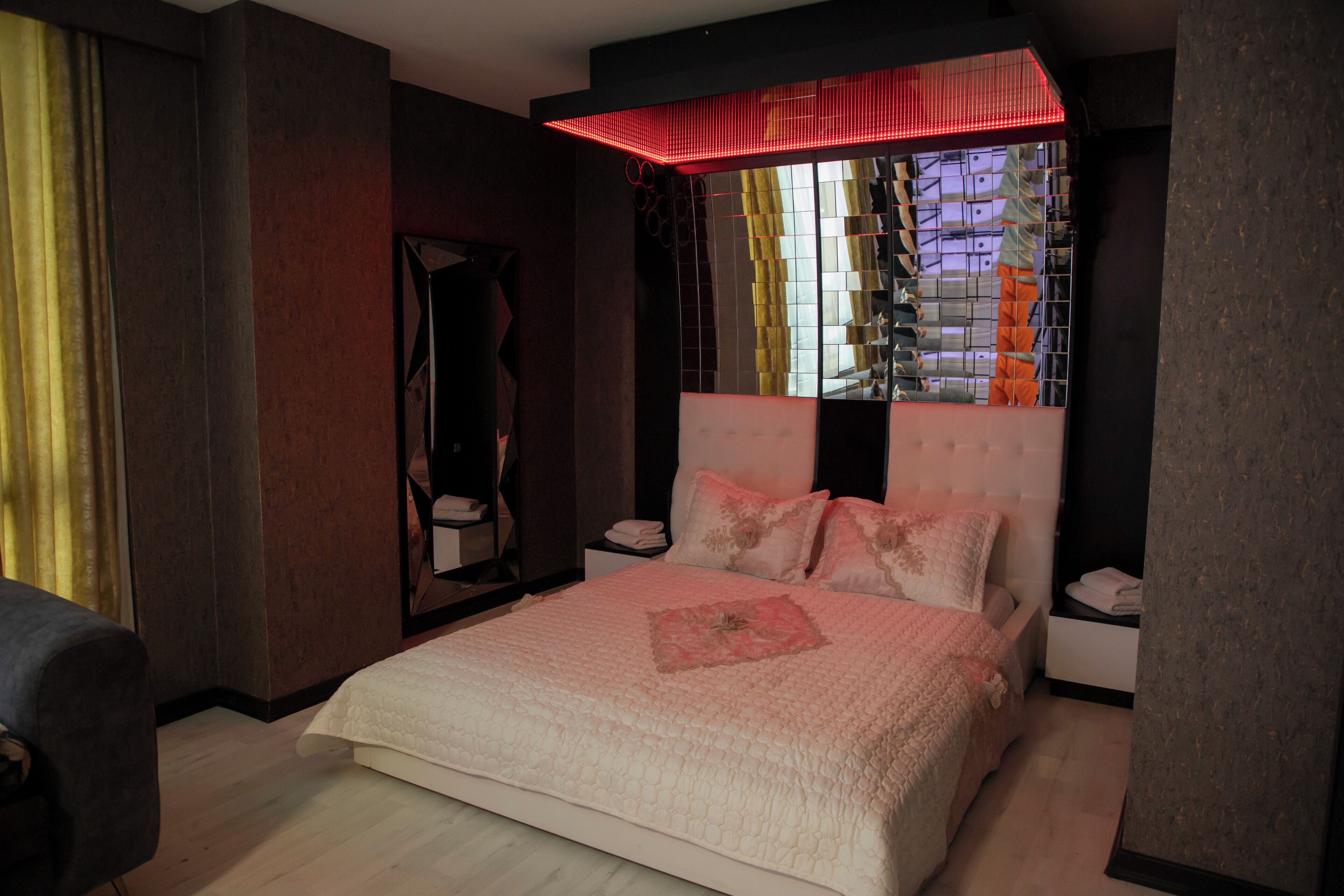 Un dormitorio con una cama grande, un espejo y una lámpara roja sobre la cama.